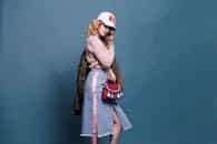 Trendy fashion model poses in a stylish studio setting, showcasing a chic outfit with accessories.