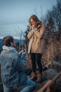 A man proposes to a woman outdoors, capturing a romantic and emotional moment.