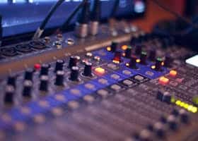 Close-up of a professional audio mixing console with glowing LED indicators.
