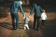 A family of four walks hand in hand on a path, enjoying a sunny day outdoors.