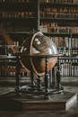 A vintage globe displayed in a historic library filled with old books.