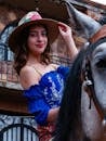 A young woman smiles while sitting on a horse, wearing traditional attire in Ciudad de México.
