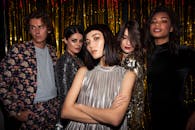 Chic group of young adults posing in glamorous attire, ready for a fashionable night out.