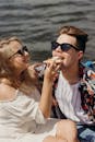 A young couple shares a joyful moment eating pizza together at the beach.