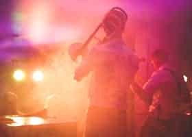 Vibrant live music performance featuring a trombone player on stage in a nightclub setting.