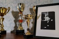 A collection of trophies with a framed black and white portrait on a shelf.