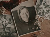 An arrangement of vintage family photos with dried flowers and film negatives, evoking nostalgia.