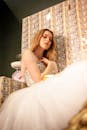 A stylish woman in a glamorous dress poses in front of a wall adorned with cash, highlighting fashion and luxury.