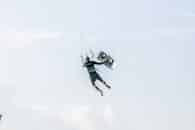 Thrilling kiteboarding action captured mid-air against a clear blue sky, showcasing adventure sports.