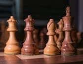 Close-up of wooden chess pieces on a chessboard, showcasing strategic focus.