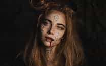 Eerie portrait of a woman with intricate face paint and dark makeup, perfect for Halloween themes.