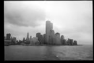 Grayscale view of New York City skyline featuring the Twin Towers across the harbor.