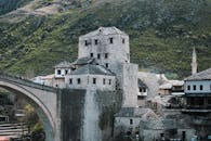 View of the iconic stone buildings and bridge in Mostar, Bosnia, highlighting its historic architecture and picturesque setting.
