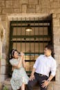 A cheerful couple posing with a vintage camera in front of a stone wall.