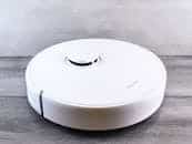 Sleek white robot vacuum cleaner on a wooden floor, perfect for smart home setups.