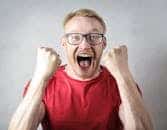 A cheerful man in a red shirt expressing excitement indoors.