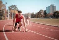 Male athlete in starting position on outdoor track with blurred background.