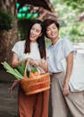 Two smiling women enjoy a day out shopping with fresh vegetables in a wicker basket.