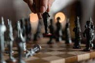 Hand placing unique chess piece on board, evoking strategy and intelligence.