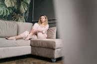 Blonde woman in elegant sleepwear relaxing on a stylish couch indoors.