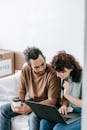 A couple sitting together on a sofa using a laptop, enjoying leisure time indoors.