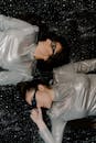 Two women in silver attire with sunglasses on a starry backdrop