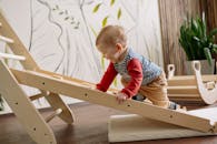 A young child enjoys climbing a wooden toy ladder indoors, promoting playtime and activity.