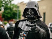 Darth Vader cosplayer pointing in an outdoor setting, showcasing detailed costume and helmet.
