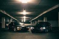 Two classic Honda cars parked in a dimly lit underground garage with a moody atmosphere.