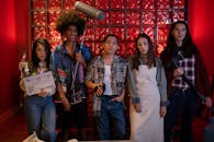 A diverse group of five people standing with film equipment indoors. Creative scene with vibrant red background.