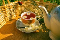 A serene setting with herbal tea infused with chamomile, placed beside a teapot, outdoors.