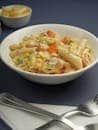 Delicious creamy penne pasta served with mixed vegetables on a dark table.
