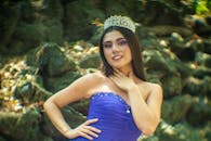 A woman in a blue gown and tiara posing outdoors, evoking princess charm.