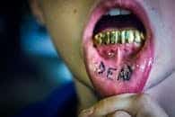 Intense close-up of gold grills and a tattooed tongue, emphasizing bold fashion in Seattle.