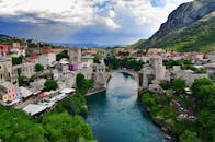 Captivating aerial shot of Stari Most bridge in Mostar, Bosnia, framed by historic architecture and lush greenery.