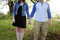 A young couple holding hands outdoors in a park, enjoying a sunny day.